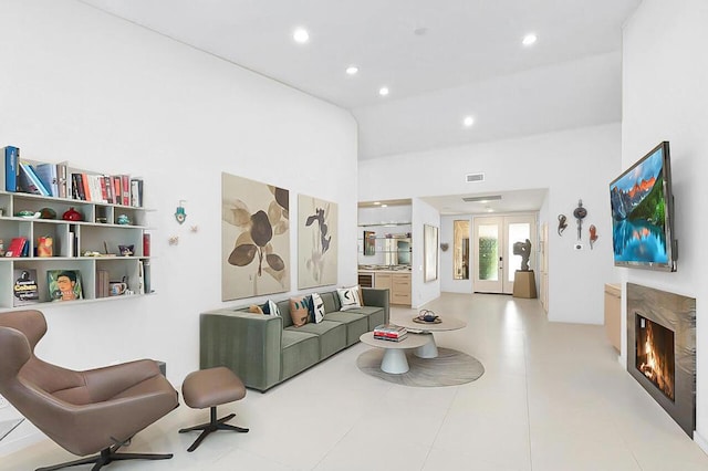 living room featuring a high end fireplace, french doors, and lofted ceiling