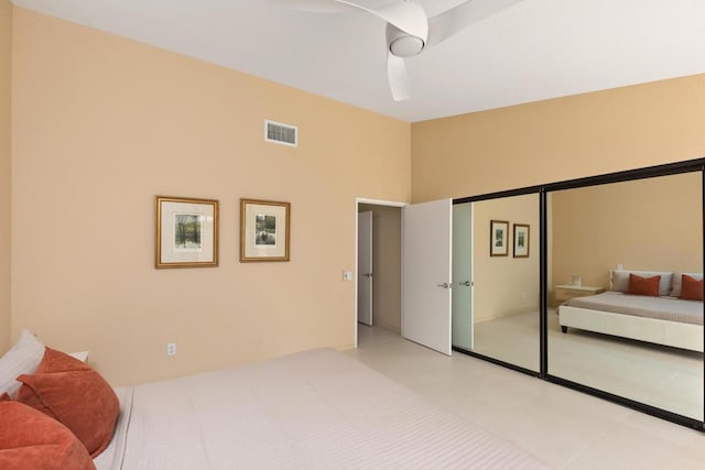 bedroom with ceiling fan, light tile patterned floors, and a closet