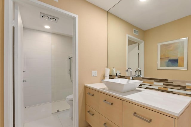 bathroom featuring vanity, tile patterned floors, toilet, tiled shower, and tasteful backsplash