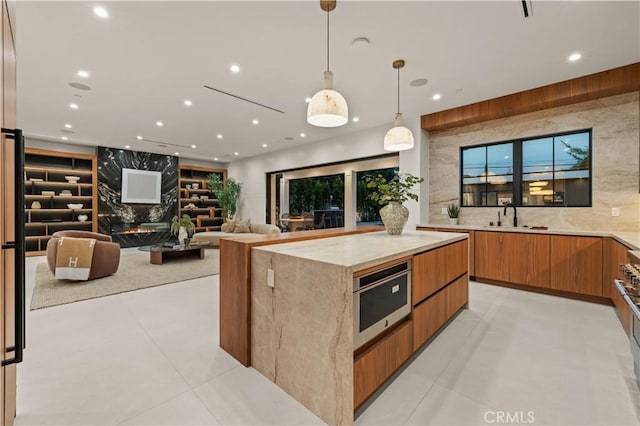 kitchen with a spacious island, sink, hanging light fixtures, stainless steel oven, and light tile patterned flooring