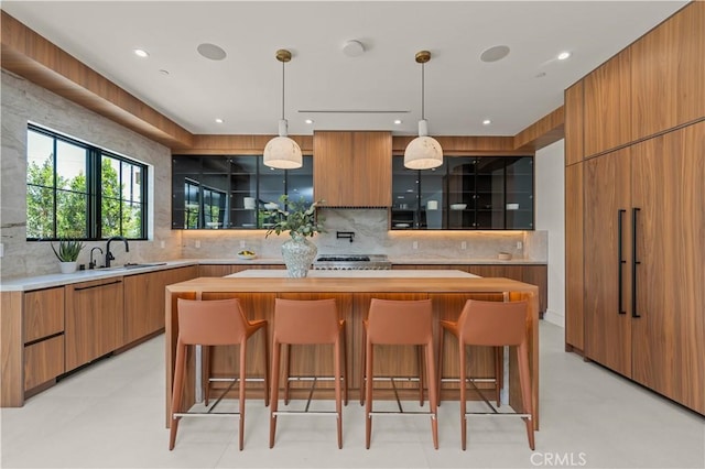 kitchen featuring pendant lighting, a center island, decorative backsplash, sink, and a breakfast bar