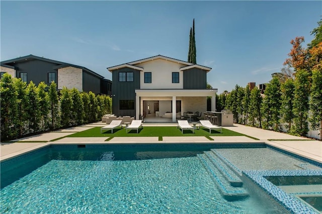 rear view of house with a pool with hot tub, a patio area, and exterior kitchen