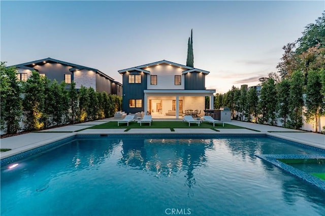 back house at dusk with an outdoor hangout area, a patio area, and an outdoor structure