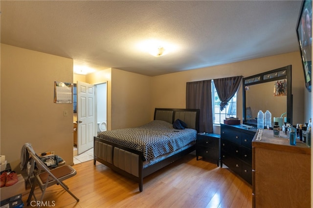 bedroom with a textured ceiling and light hardwood / wood-style floors