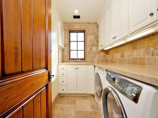 clothes washing area with cabinets, washing machine and clothes dryer, and sink