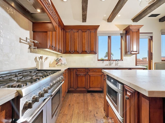 kitchen featuring light hardwood / wood-style floors, appliances with stainless steel finishes, beamed ceiling, and tasteful backsplash