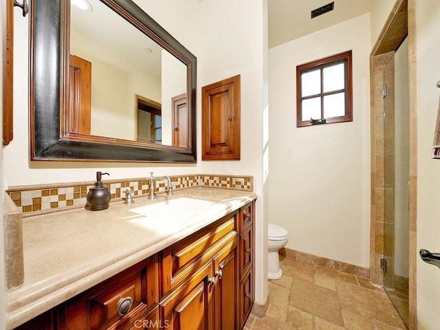 bathroom featuring tasteful backsplash, vanity, a shower, and toilet