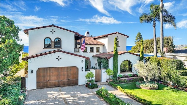 mediterranean / spanish house featuring a garage and a front yard