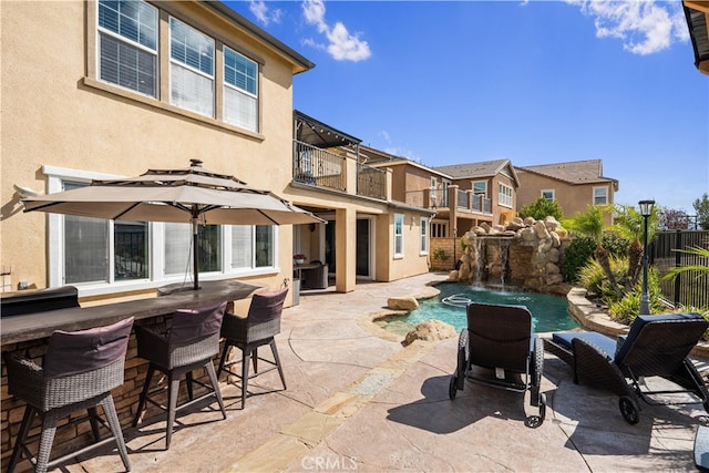 view of patio / terrace featuring a bar, a balcony, and pool water feature