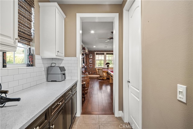 kitchen featuring ceiling fan, white cabinets, light stone countertops, dark brown cabinets, and light wood-type flooring