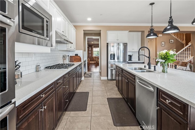 kitchen featuring appliances with stainless steel finishes, white cabinets, pendant lighting, ornamental molding, and sink