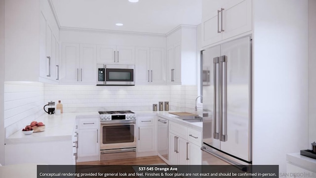 kitchen with backsplash, hardwood / wood-style floors, sink, white cabinetry, and appliances with stainless steel finishes