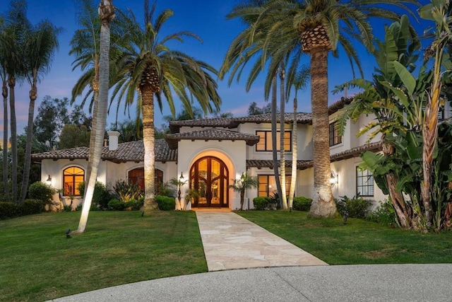 mediterranean / spanish-style house with a lawn and french doors