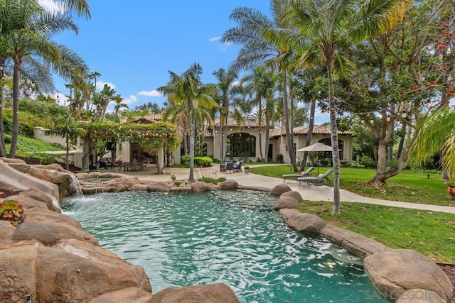 view of swimming pool featuring a lawn, pool water feature, and a patio