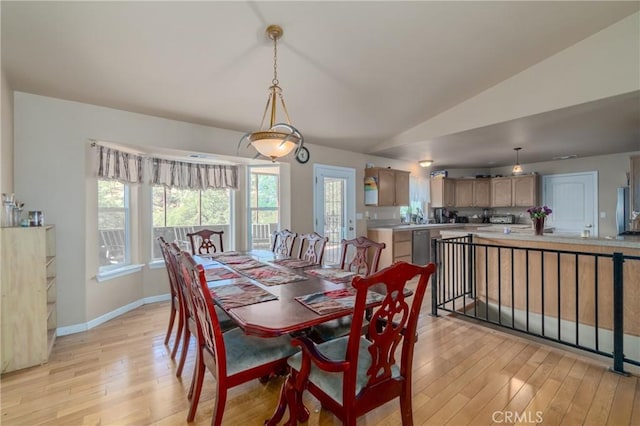 dining area with light wood-type flooring and vaulted ceiling