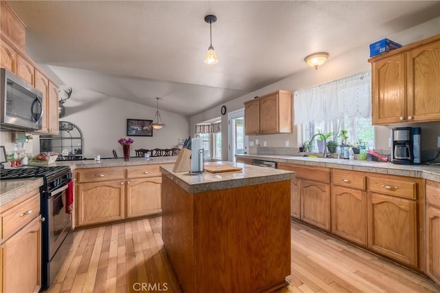 kitchen with appliances with stainless steel finishes, sink, lofted ceiling, pendant lighting, and a center island