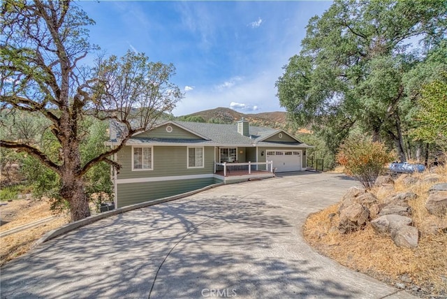 single story home with aphalt driveway, a chimney, and an attached garage