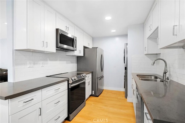 kitchen featuring backsplash, stainless steel appliances, sink, light hardwood / wood-style flooring, and white cabinets