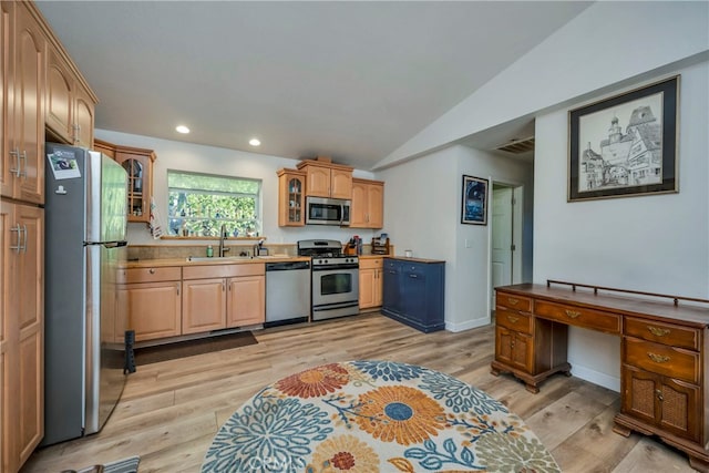 kitchen featuring appliances with stainless steel finishes, lofted ceiling, light wood-type flooring, and sink