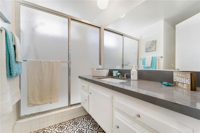 bathroom featuring tile patterned floors, a shower with door, and vanity