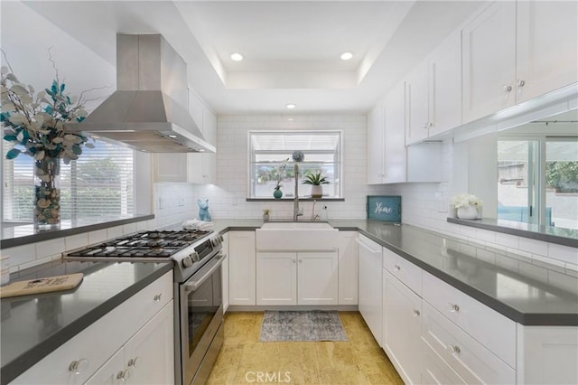 kitchen featuring stainless steel range, sink, wall chimney range hood, backsplash, and white cabinets