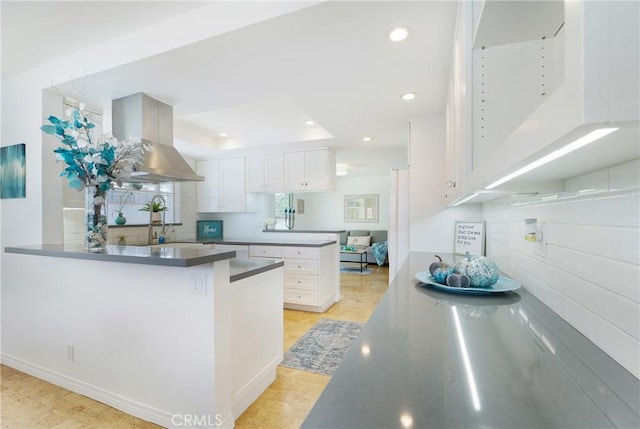 kitchen featuring white cabinetry, sink, tasteful backsplash, range hood, and kitchen peninsula