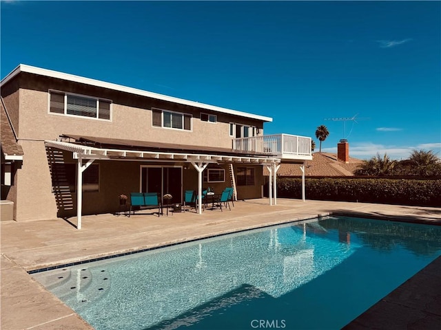 rear view of property with a pergola, a patio area, a balcony, and a fenced in pool