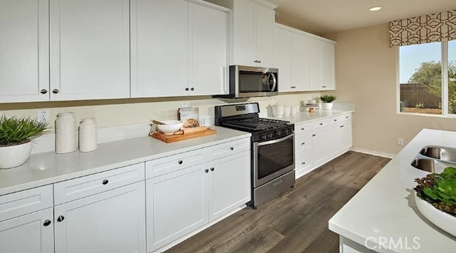 kitchen featuring stainless steel appliances, white cabinets, and dark wood-type flooring