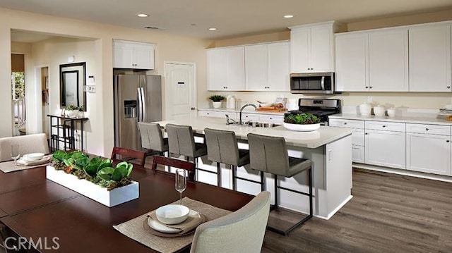 kitchen featuring sink, a kitchen island with sink, white cabinetry, appliances with stainless steel finishes, and dark hardwood / wood-style floors