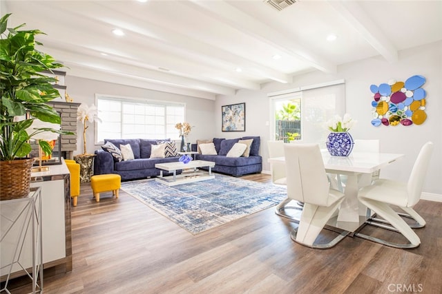 living room with wood-type flooring, beamed ceiling, and a wealth of natural light