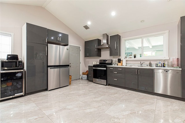 kitchen featuring appliances with stainless steel finishes, vaulted ceiling, wine cooler, wall chimney exhaust hood, and sink