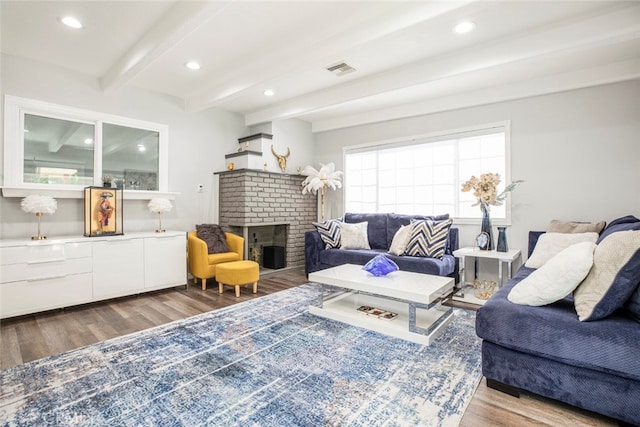 living room featuring wood-type flooring, a brick fireplace, and beam ceiling