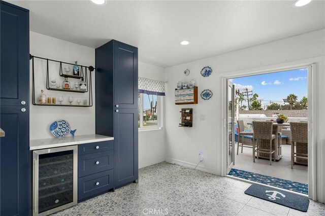 bar with blue cabinets and wine cooler