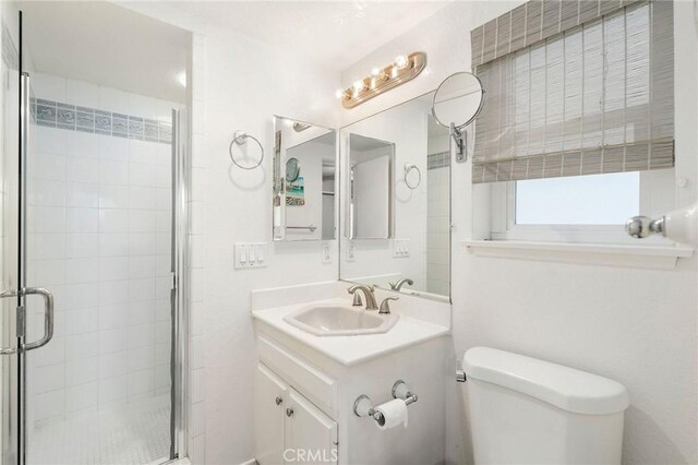 bathroom with walk in shower, vanity, and toilet