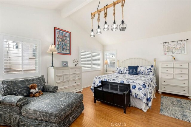 bedroom with lofted ceiling with beams and light wood-type flooring