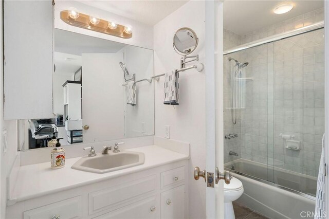 full bathroom with combined bath / shower with glass door, vanity, toilet, and tile patterned flooring