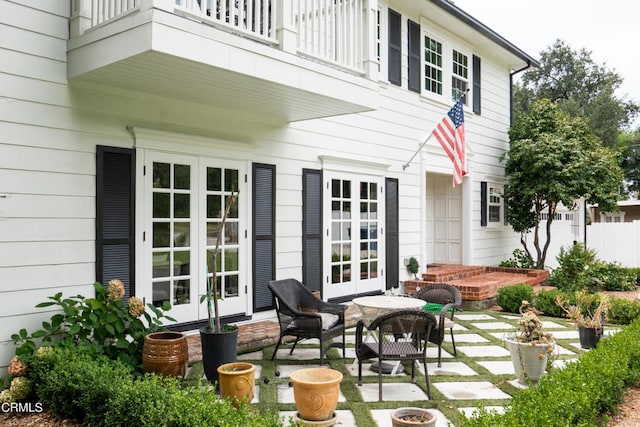 rear view of house with french doors, a balcony, and a patio