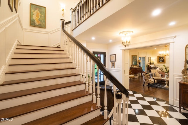 stairway with wood-type flooring and a notable chandelier