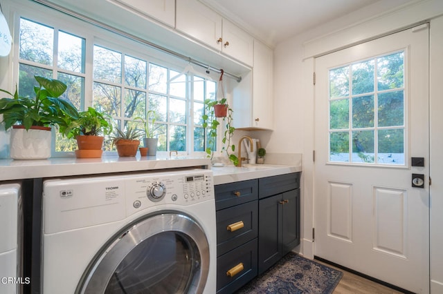 clothes washing area featuring cabinets, light hardwood / wood-style floors, separate washer and dryer, and sink