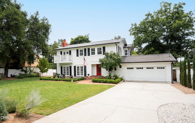 colonial inspired home with a balcony, a front yard, and a garage