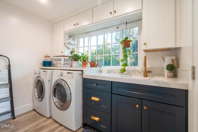 clothes washing area with separate washer and dryer, cabinets, sink, and light hardwood / wood-style floors