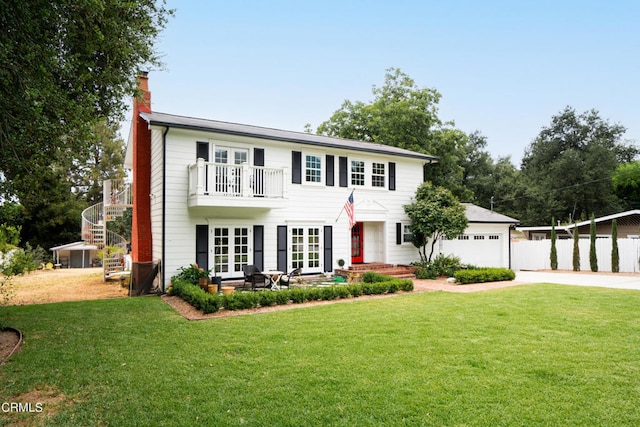 colonial inspired home with a garage, a balcony, and a front lawn