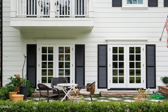 view of exterior entry featuring a balcony and french doors