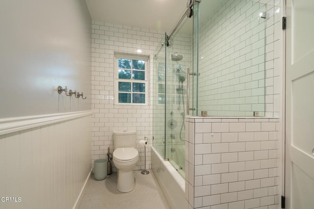 bathroom with combined bath / shower with glass door and toilet