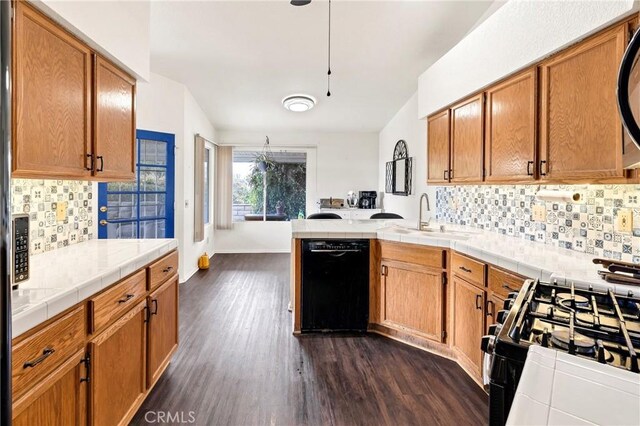 kitchen featuring dark wood-type flooring, sink, tasteful backsplash, and black appliances