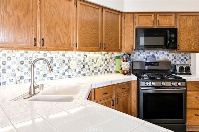 kitchen featuring sink, tile counters, gas stove, and tasteful backsplash