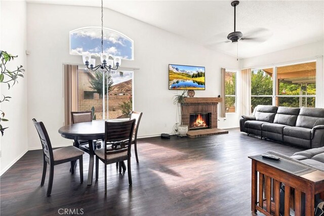 dining room with ceiling fan with notable chandelier, a brick fireplace, lofted ceiling, and dark hardwood / wood-style floors