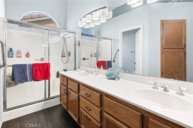 bathroom with wood-type flooring, a shower with door, and vanity