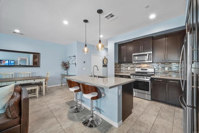 kitchen featuring pendant lighting, a breakfast bar, a kitchen island with sink, sink, and appliances with stainless steel finishes