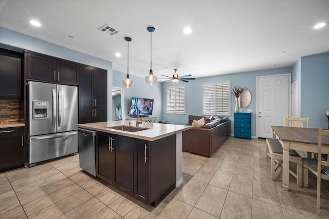 kitchen featuring ceiling fan, sink, decorative light fixtures, a center island with sink, and stainless steel appliances